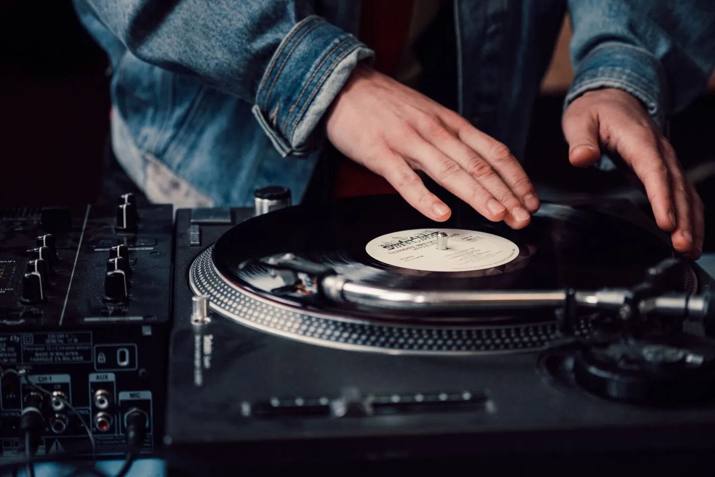A DJ mixing vinyl records on a turntable.